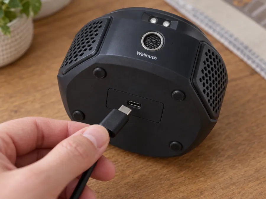 A hand plugs the USB-C cable into the bottom of the unit